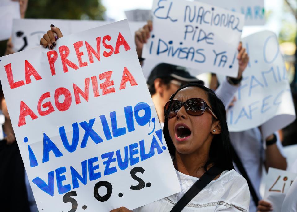 An employee of the newspaper El Nacional holds up a sign that reads in Spanish "The press is dying, help Venezuela", during a protest outside the Cadivi a agency which controls foreign currency in Caracas, Venezuela, Tuesday, Jan. 28, 2014. The newspaper is scrambling for newsprint as worsening shortages threaten to take several publications out of circulation in the coming weeks as reserves of newsprint have fallen to an all-time low. (AP Photo/Fernando Llano)