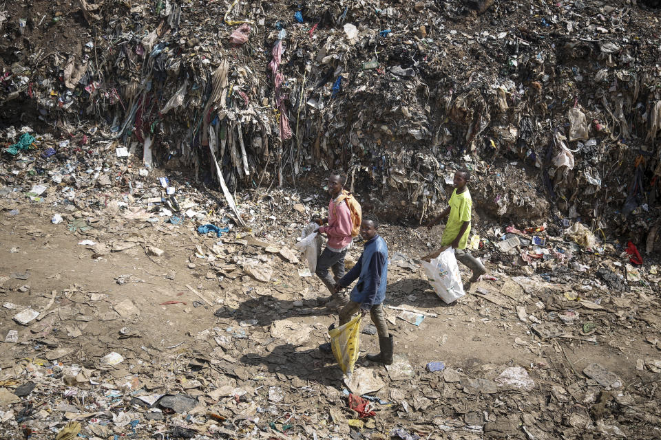 Mohamed Nassur, 17, left, Peter Kihika, 16, center, and Dominic Munyoki, 15, right, scavenge for scrap metal to sell at Kenya's largest landfill Dandora where Mohamed now works after his mother lost her job and his school was closed due to the coronavirus pandemic, in Nairobi, Kenya Saturday, Sept. 26, 2020. The United Nations says the COVID-19 pandemic risks significantly reducing gains made in the fight against child labor, putting millions of children at risk of being forced into exploitative and hazardous jobs, and school closures could exacerbate the problem. (AP Photo/Brian Inganga)