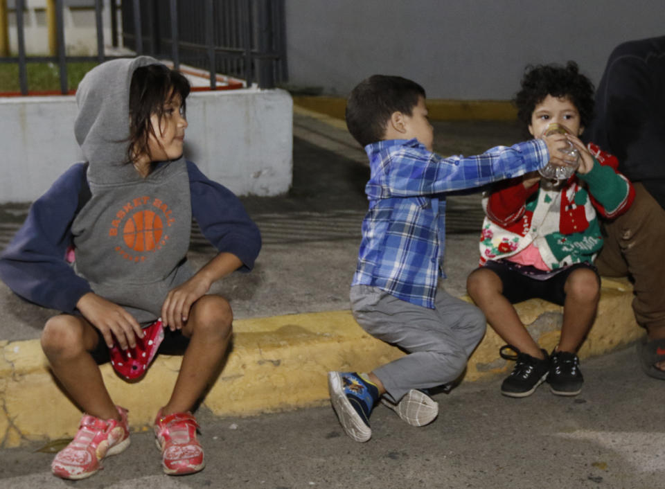 Children wait for their group to be ready to leave San Pedro Sula, Honduras by foot before dawn Tuesday, March 30, 2021. The migrant group aims to reach the U.S. (AP Photo/Delmer Martinez)