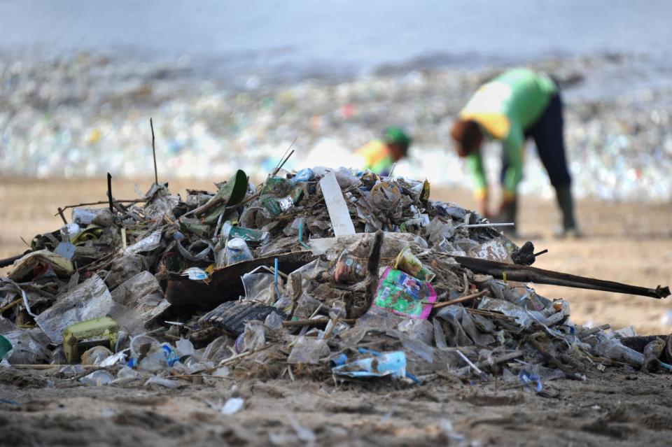 Workers remove litter from a popular beach in Bali - AFP