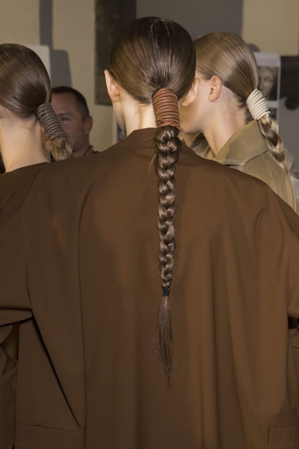 <p>Long, glossy braids were secured with a leather coil backstage at Max Mara.</p>