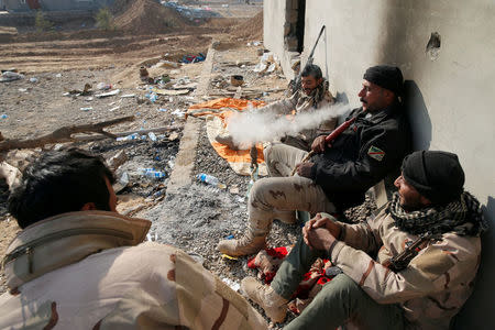 Members of the Iraqi Army smoke waterpipe as they rest during clashes with Islamic State militants at the south of Mosul, Iraq December 12, 2016. REUTERS/Ammar Awad.