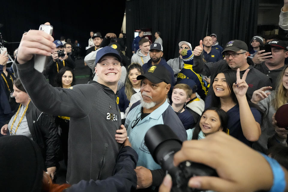 Michigan quarterback J.J. McCarthy takes a picture with fans during media day ahead of the national championship NCAA College Football Playoff game between Washington and Michigan Saturday, Jan. 6, 2024, in Houston. The game will played Monday. (AP Photo/David J. Phillip)