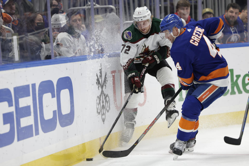 Arizona Coyotes center Travis Boyd (72) and New York Islanders defenseman Andy Greene (4) fight for a puck during the first period of an NHL hockey game, Friday, Jan. 21, 2022, in Elmont, N.Y. (AP Photo/Corey Sipkin).