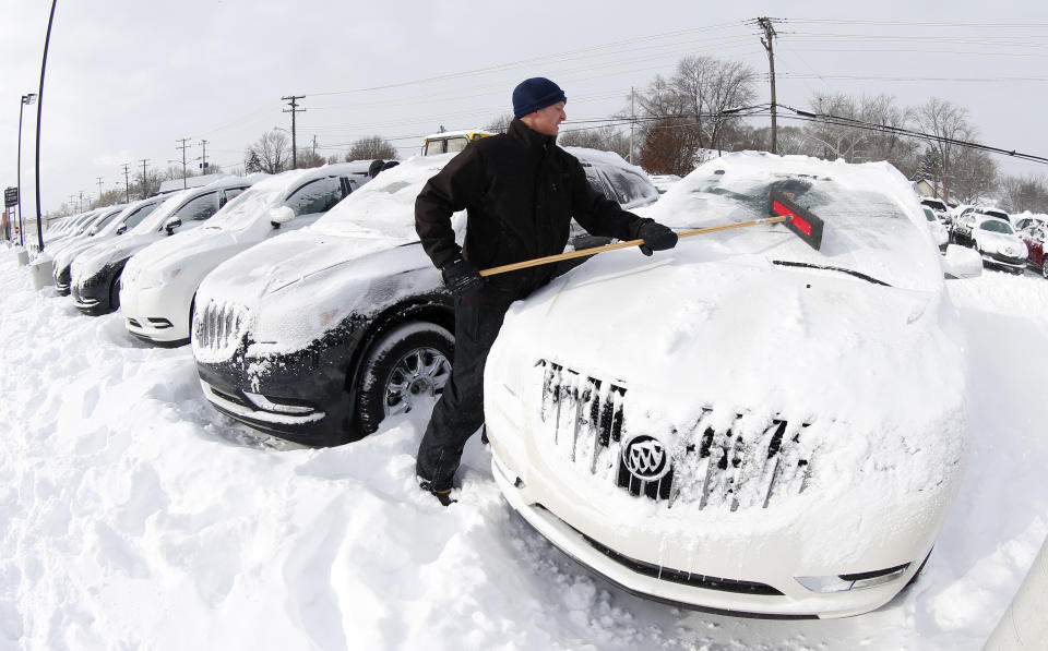 Matt Frame brushes off a Buick at Ray Laethem Buick-GMC in Detroit, Monday, Jan. 6, 2014. Michigan residents are preparing for diving temperatures as they dig out from more than 15 inches of snow in places. Snow wrapped up after starting during the weekend. Roads are slippery, with numerous crashes. In the southern Lower Peninsula, temperatures are to drop late Monday or early Tuesday as low as minus 15. (AP Photo/Paul Sancya)