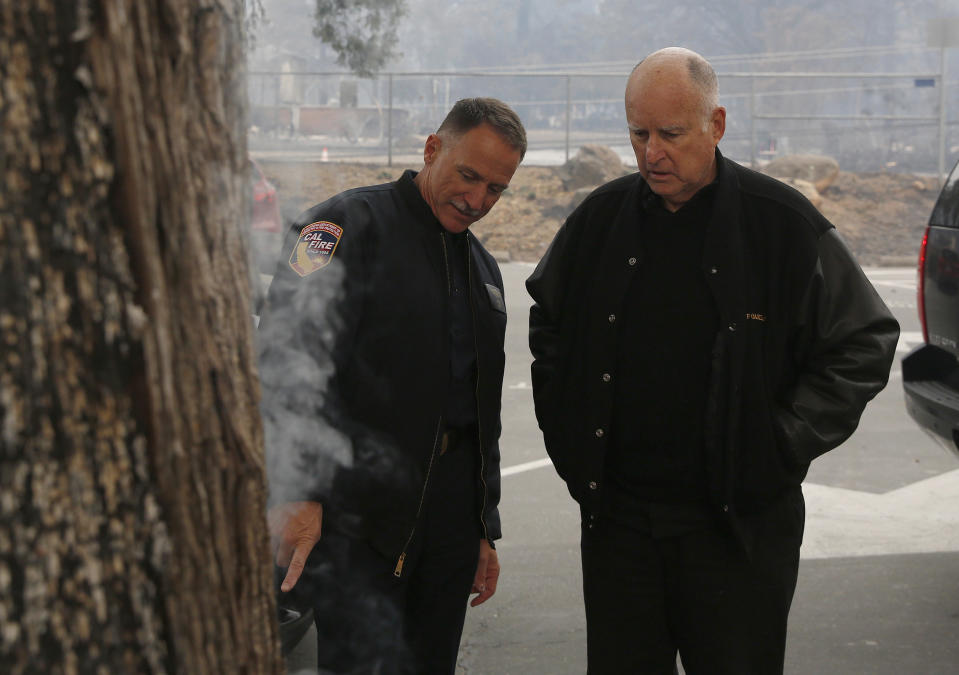 FILE - Ken Pimlott, director of the California Department of Forestry and Fire Protection, left, shows California Gov. Jerry Brown where smoke is still rising from a smoldering tree during a tour of the fire ravaged Paradise Elementary School, on Nov. 14, 2018, in Paradise, Calif. Brown has called California's mega fires "the new abnormal" as climate change turns the state warmer and drier. With the help of Pimlott, he convened a group at his rural Colusa County ranch in September 2021, to discuss what could be done to save California's forests. (AP Photo/Rich Pedroncelli, File)