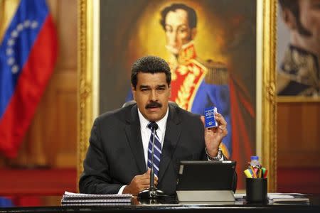 Venezuela's President Nicolas Maduro holds a copy of the country's constitution as he speaks during a news conference at Miraflores Palace in Caracas December 30, 2014. REUTERS/Carlos Garcia Rawlins