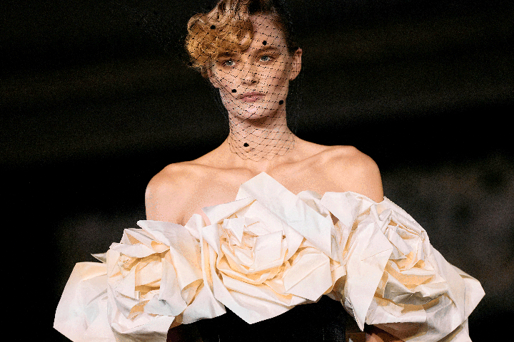 a woman in a white rosette dress and black netted veil