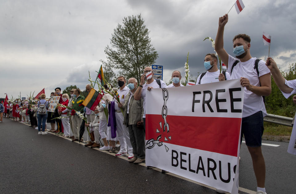 Supporters of Belarus opposition from Lithuania hold and wave historical Belarusian flags during the "Freedom Way", a human chain of about 50,000 strong from Vilnius to the Belarusian border, near Medininkai, Lithuanian-Belarusian border crossing east of Vilnius, Lithuania, Sunday, Aug. 23, 2020. In Aug. 23, 1989, around 2 million Lithuanians, Latvians, and Estonians joined forces in a living 600 km (375 mile) long human chain Baltic Way, thus demonstrating their desire to be free. Now, Lithuania is expressing solidarity with the people of Belarus, who are fighting for freedom today. (AP Photo/Mindaugas Kulbis)