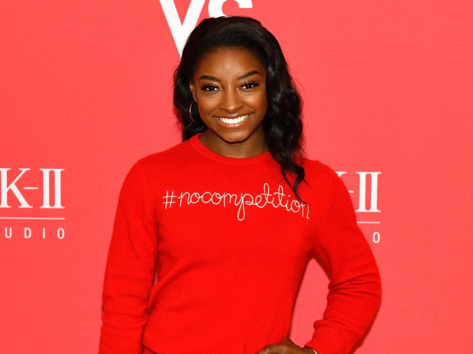 simone biles poses on a red carpet