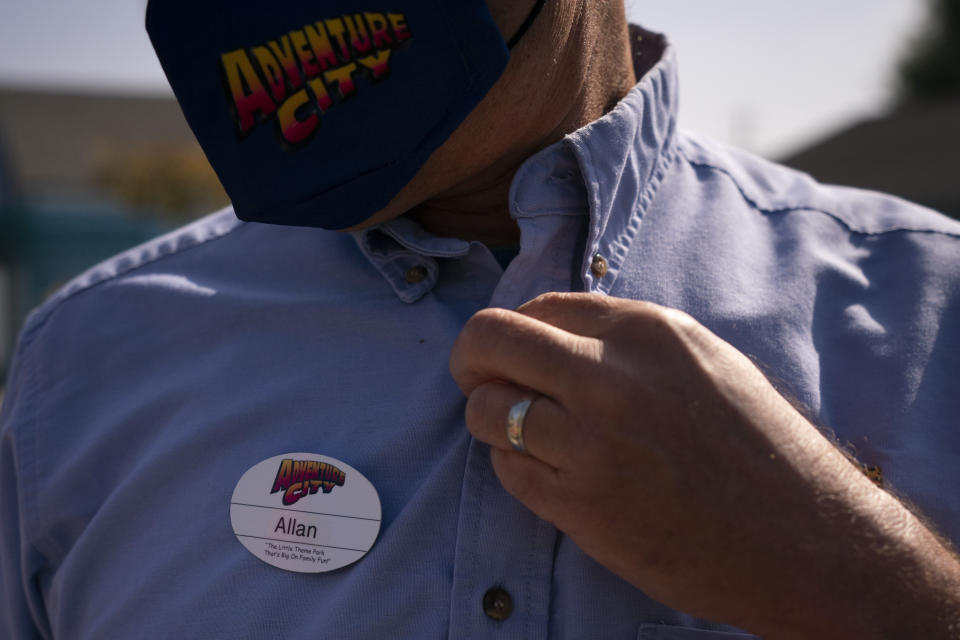 Allan Ansdell Jr., owner and president of Adventure City amusement park, buttons his uniform on the day of reopening at the park in Anaheim, Calif., Friday, April 16, 2021. The family-run amusement park that had been shut since March last year because of the coronavirus pandemic reopened on April 16. "It's mixed emotions," he said, recalling the day he let go of most of his 150 employees, including his wife. Only a handful remained at the park. "Parks are seasonal. Sometimes you have a rainy month. We always have enough in our reserves for three or four months of who knows what. But nobody has a reserve for a year," Ansdell Jr. said. It's been hard for all of us. "I'm glad that we are getting through it. I'm glad we are reaching the end." (AP Photo/Jae C. Hong)