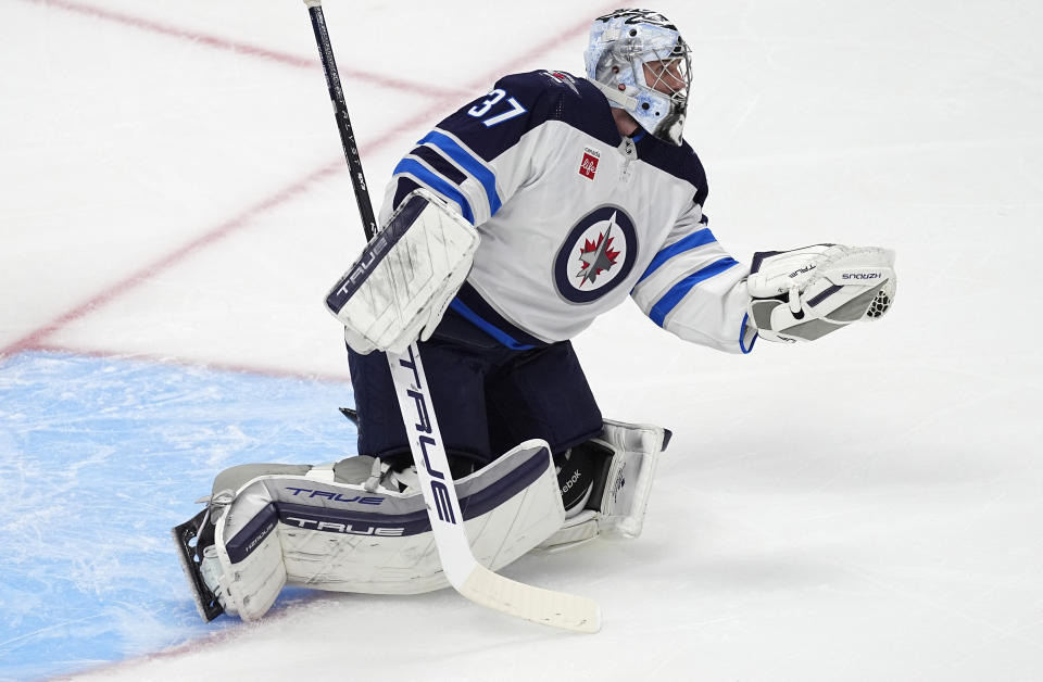 Winnipeg Jets goaltender Connor Hellebuyck makes a glove save against the Colorado Avalanche during the first period of Game 3 of an NHL hockey Stanley Cup first-round playoff series Friday, April 26, 2024, in Denver. (AP Photo/David Zalubowski)