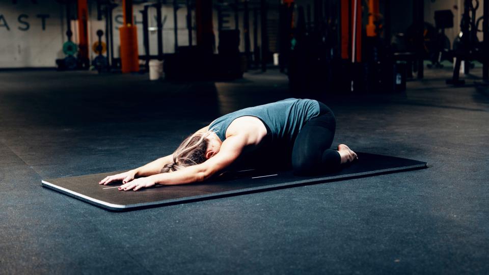 Tia performing child's pose on her yoga mat: Pliability app