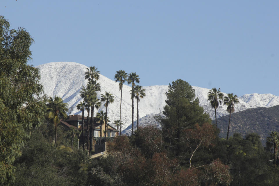 Snowy mountains provide a backdrop to suburban palm trees northeast of Los Angeles, Calif., on Sunday, Feb. 26, 2023, after a major winter storm swept through the state. Snow fell to unusually low levels in Southern California. (AP Photo/John Antczak)