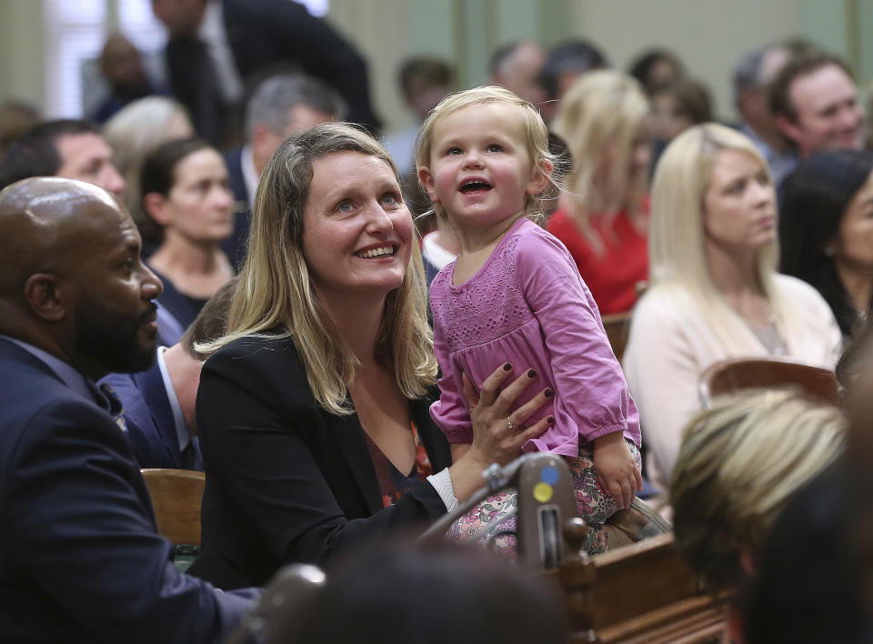 FILE— Assemblywoman Buffy Wicks, a Democrat, and her daughter, Josephine, 2, look up to the Assembly Gallery during the legislative session on Monday, Dec. 3, 2018, in Sacramento, Calif. California will be the first state to require companies that provide online services attractive to children to put the child's interest first, Gov. Gavin Newsom said Thursday, Sept. 15, 2022. (AP Photo/Rich Pedroncelli, File)