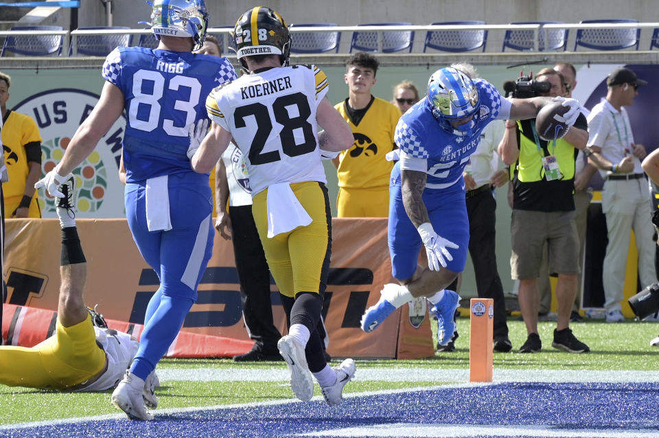 Kentucky running back Chris Rodriguez Jr. (24), right, scores on a 5-yard touchdown pass play as tight end Justin Rigg (83) and Iowa defensive back Jack Koerner (28) watch during the first half of the Citrus Bowl NCAA college football game, Saturday, Jan. 1, 2022, in Orlando, Fla. (AP Photo/Phelan M. Ebenhack)