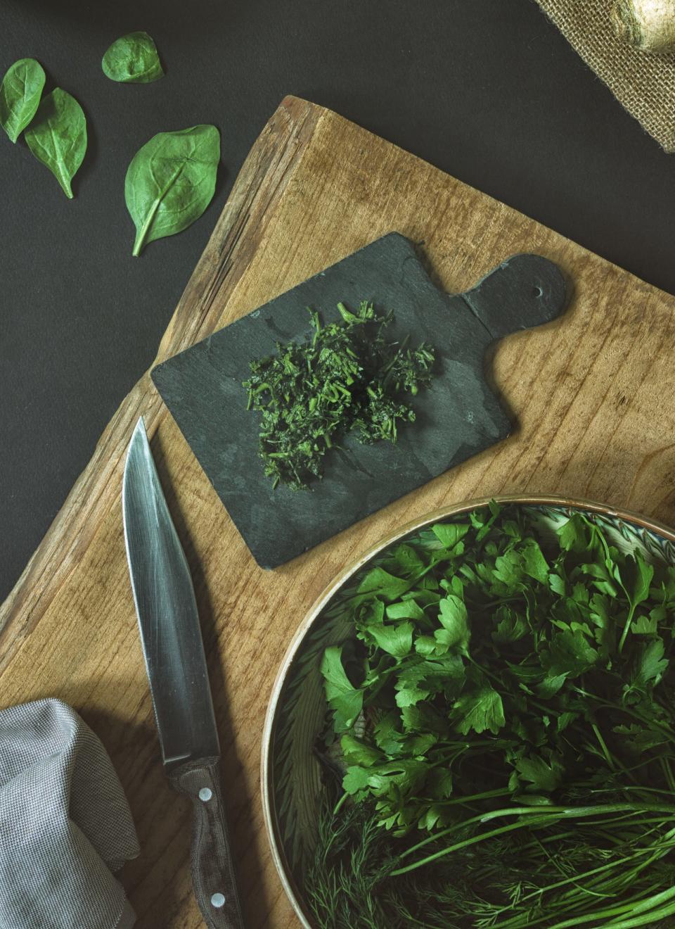 Chopped herbs on a wooden cutting board.