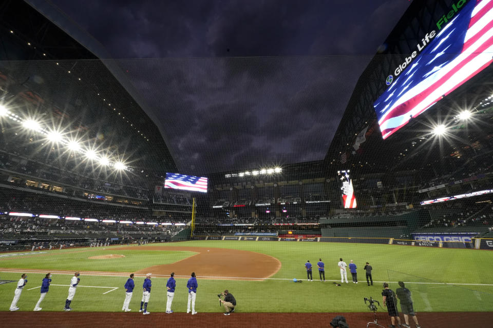 Members of the Los Angeles Dodgers stand during the national anthem before Game 7 of a baseball National League Championship Series Sunday, Oct. 18, 2020, in Arlington, Texas. Most of the seats of a new $1.2 billion, 40,518-capacity will be empty among the smallest crowd to view a World Series game in more than a century. (AP Photo/Eric Gay)