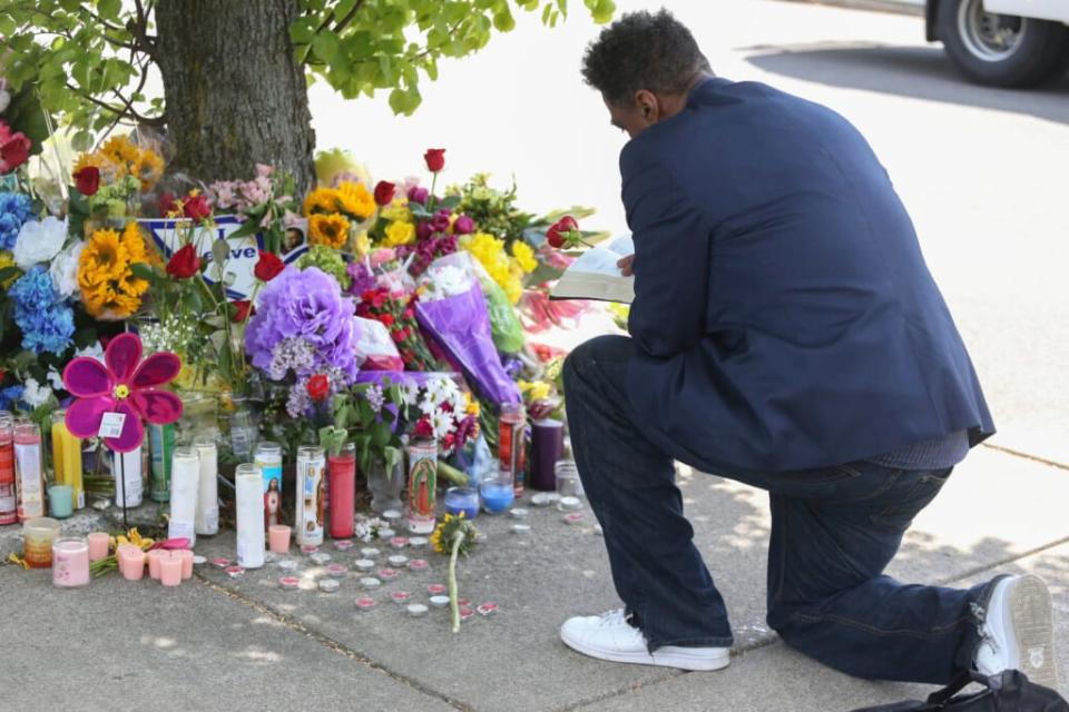 A man reads scripture at the site of a memorial honoring the victims of Saturday’s shooting on Sunday, May 15, 2022, in Buffalo, N.Y. A white 18-year-old wearing military gear and livestreaming with a helmet camera opened fire with a rifle at a supermarket, killing and wounding people in what authorities described as “racially motivated violent extremism.” (AP Photo/Joshua Bessex)