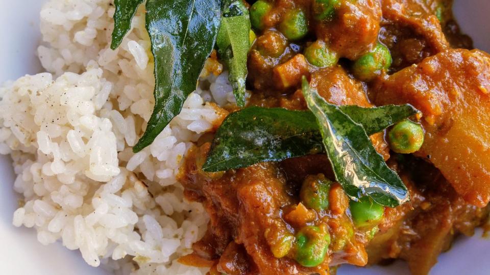 potato curry served with white rice and fried dark green curry leaves