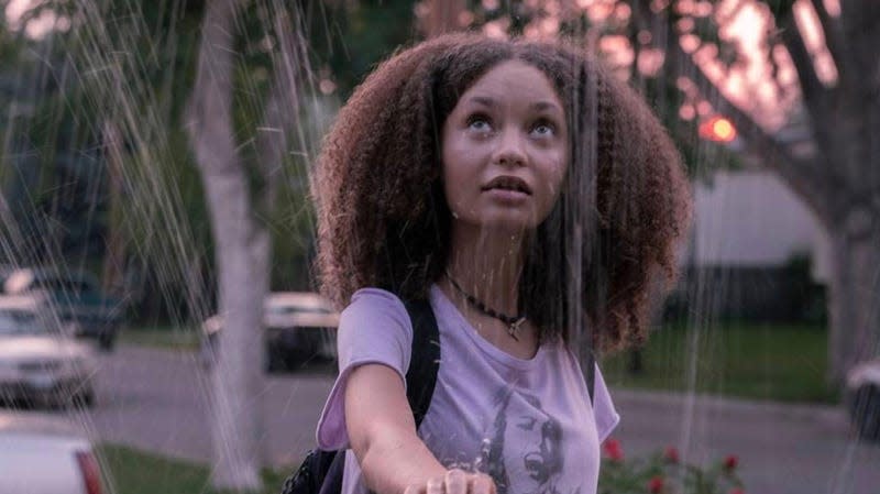 Actor Nico Parker as Sarah puts her hand through a spider web on a suburban street.