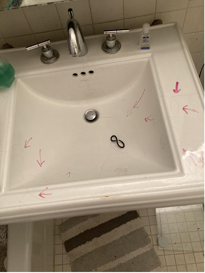 Arrows drawn on a sink pointing to hair that was left over