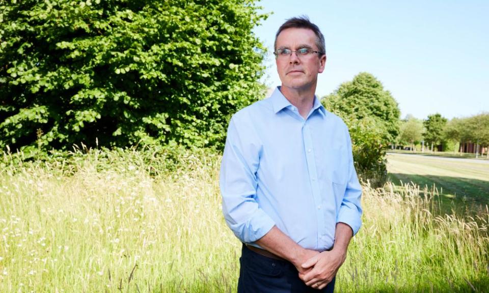 Dr Stephen Brearey stands in a field with trees behind him