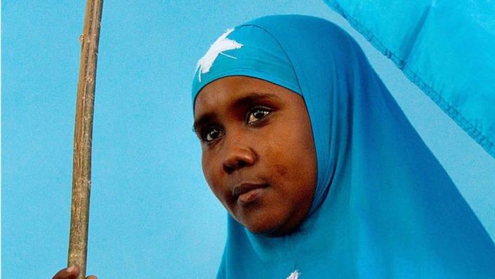 A Somali woman holds the national flag during a ceremony marking President Sheikh Sharif Sheikh Ahem&#39;s first year in office at the Villa Somalia presidential palace in Mogadishu on January 29, 2010