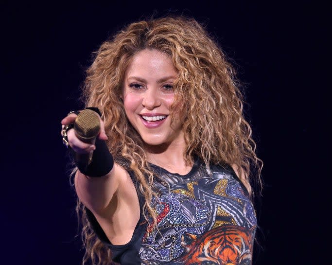 Shakira pointing her mic and smiling