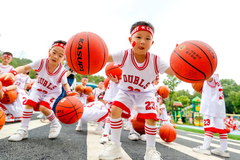 En Xiajiang, China, niños de jardín de infantes juegan con pelotas de básquet.