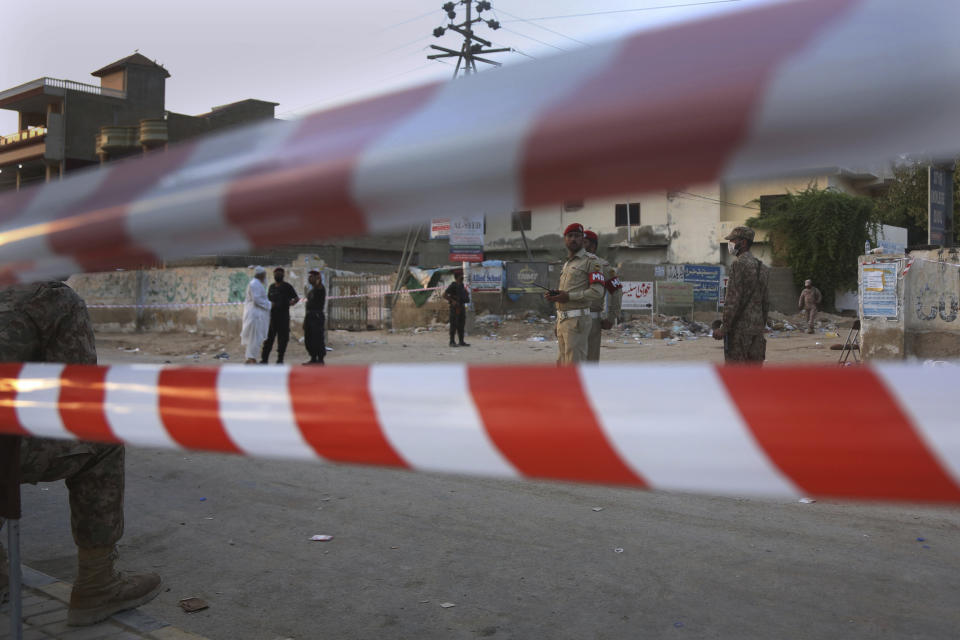 Pakistan army soldiers and police commandos stand guard while they cordon off a street leading to the site of a plane crash, in Karachi, Pakistan, Saturday, May 23, 2020. A passenger plane carrying nearly 100 passengers crashed in a crowded neighborhood near the airport in Karachi. (AP Photo/Fareed Khan)