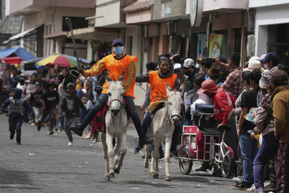 Marjory Vivanco, a la izquierda, montada en su burro El Botas se enfila a la victoria en la final de la carrera femenina durante un festival anual de esos equinos en Salcedo, Ecuador, el sábado 10 de septiembre de 2022. (AP Foto/Dolores Ochoa)