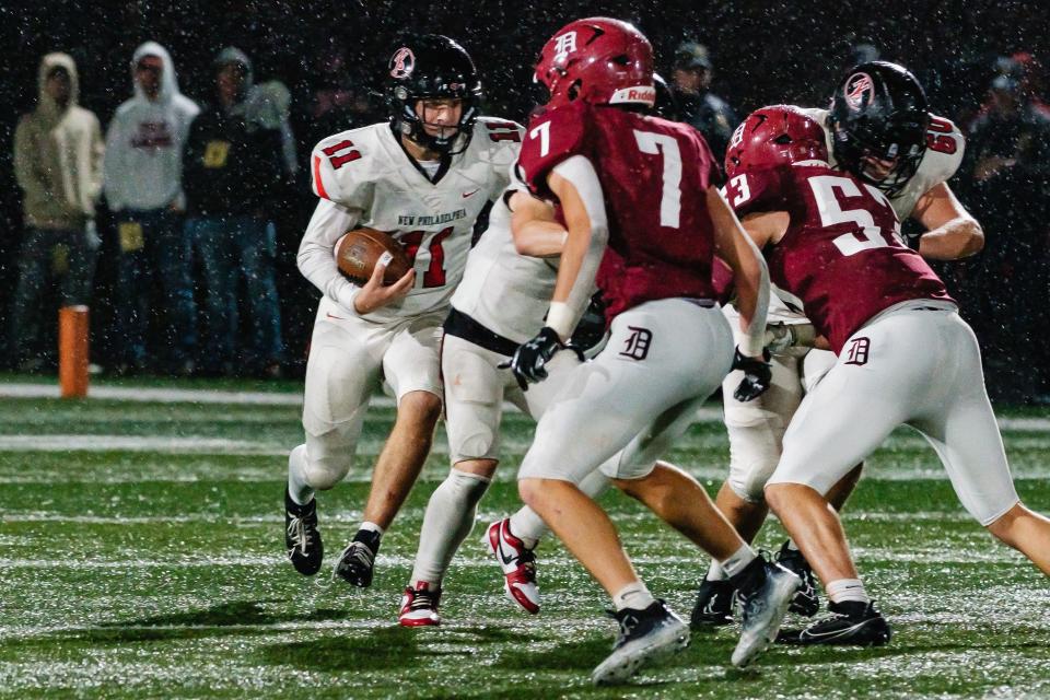 New Philadelphia quarterback Keaton Fausel runs through the rain during week 10 high school football action against Dover, Friday, Oct. 20 at the ‘Brick House’ in Dover, Ohio. This was the 120th annual Dover-Phila rivalry game, which was first played in 1896.