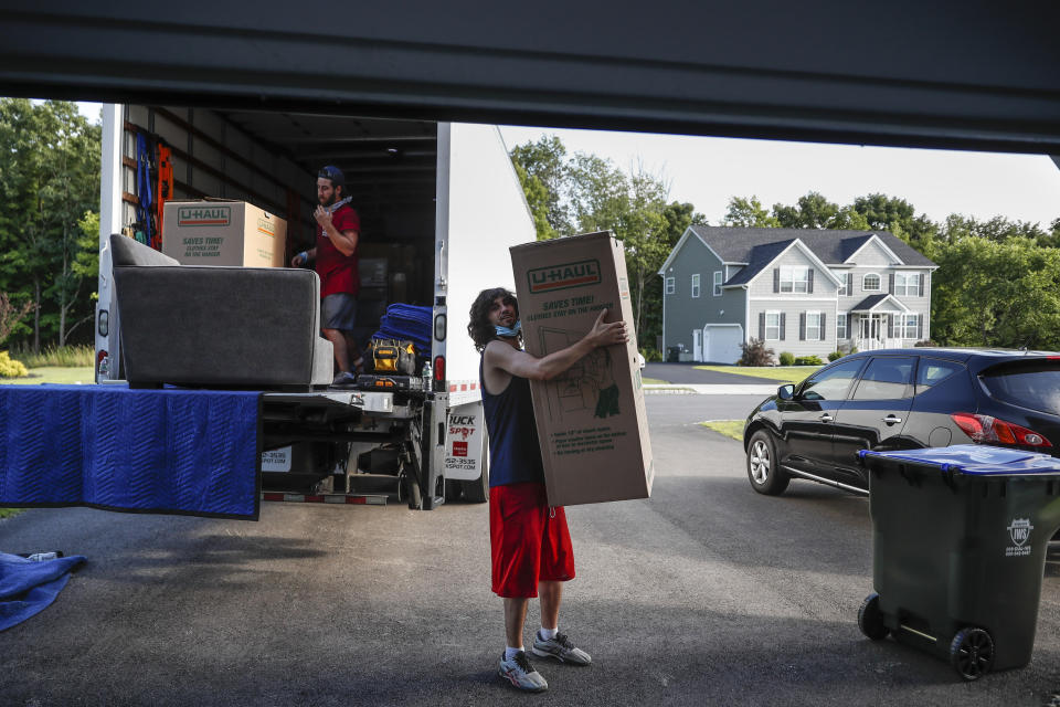 Movers unload a truckload of belongings as the Lilly family move into their new home, Tuesday, July 21, 2020, in Washingtonville, N.Y. New Yorkers anxious after weathering the worst of the coronavirus pandemic are fueling a boom in home sales and rentals around the picturesque towns and wooded hills to the north. Real estate brokers and agents describe a red-hot market recently, with many house hunters able to work from home. (AP Photo/John Minchillo)