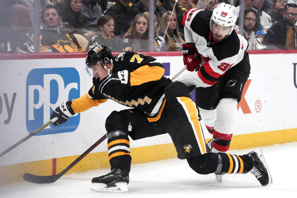 Pittsburgh Penguins' Evgeni Malkin, left, and New Jersey Devils' Kevin Bahl, right, work for puck procession in the corner during the second period of an NHL hockey game in Pittsburgh, Thursday, Nov. 16, 2023. (AP Photo/Gene J. Puskar)