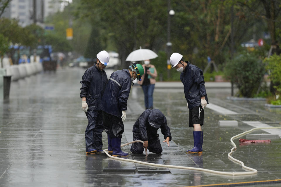 Workers check drainage hole at a square as Typhoon Hinnamnor travels toward the Korean Peninsula in Seoul, South Korea, Monday, Sept. 5, 2022. Hundreds of flights were grounded and more than 200 people evacuated in South Korea on Monday as Typhoon Hinnamnor approached the country's southern region with heavy rains and winds of up to 290 kilometers (180 miles) per hour, the strongest storm in decades. (AP Photo/Lee Jin-man)