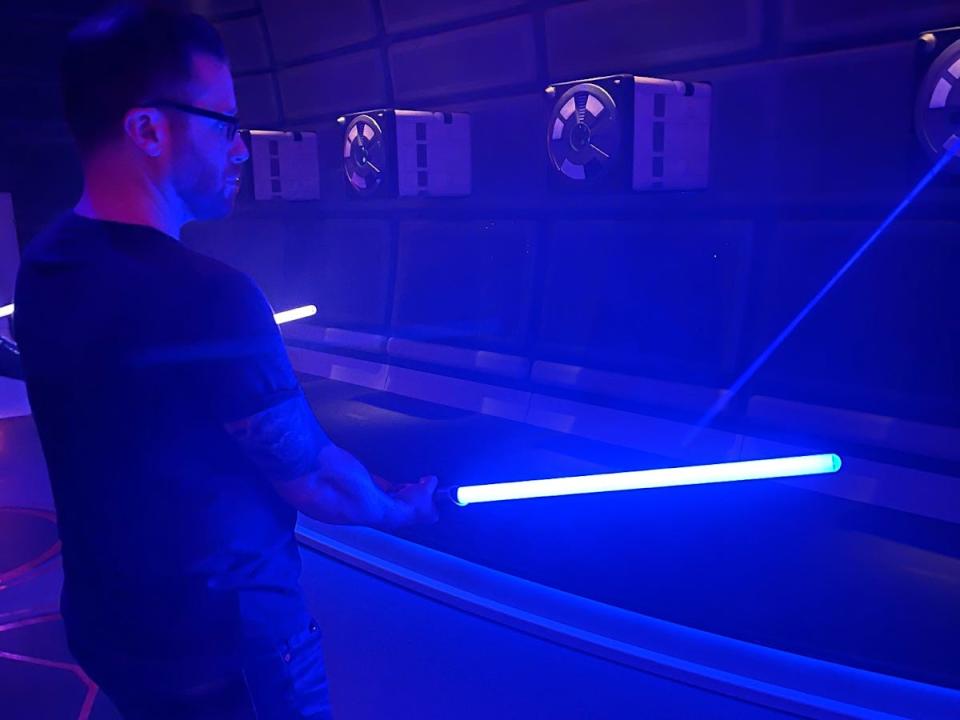 My husband doing lightsaber training, swinging a lightsaber in a dark room