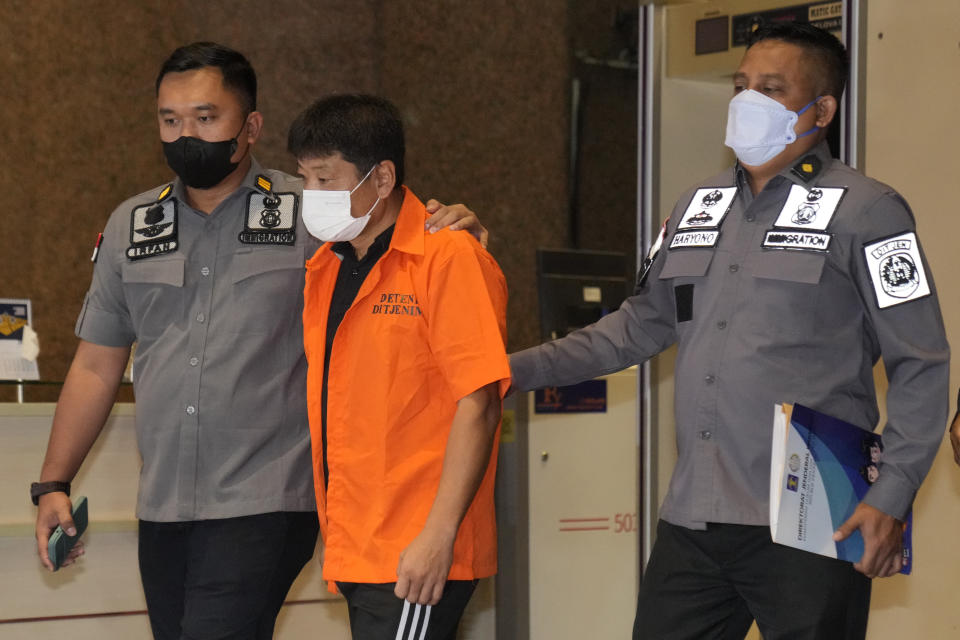 Immigration officers escort Japanese fugitive Mitsuhiro Taniguchi who was arrested on Sumatra island in early June, prior to his deportation in Jakarta, Indonesia, Wednesday, June 22, 2022. Indonesia on Wednesday deported Taniguchi who was wanted by Japanese police for COVID-19 subsidy fraud. (AP Photo/Dita Alangkara)