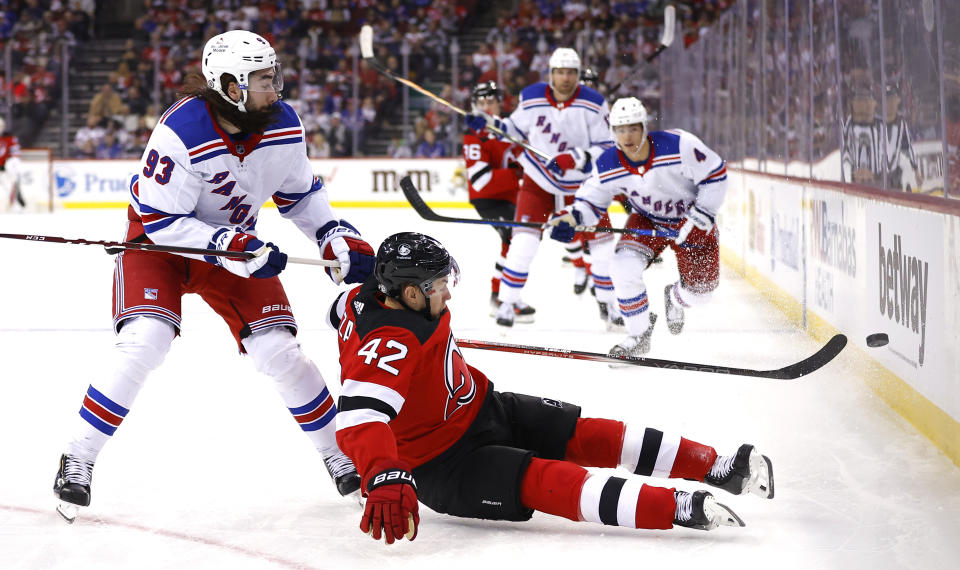 New Jersey Devils center Curtis Lazar (42) falls to the ice wile playing the puck against New York Rangers center Mika Zibanejad (93) during the second period of an NHL hockey game Saturday, Nov. 18, 2023, in Newark, N.J. (AP Photo/Noah K. Murray)