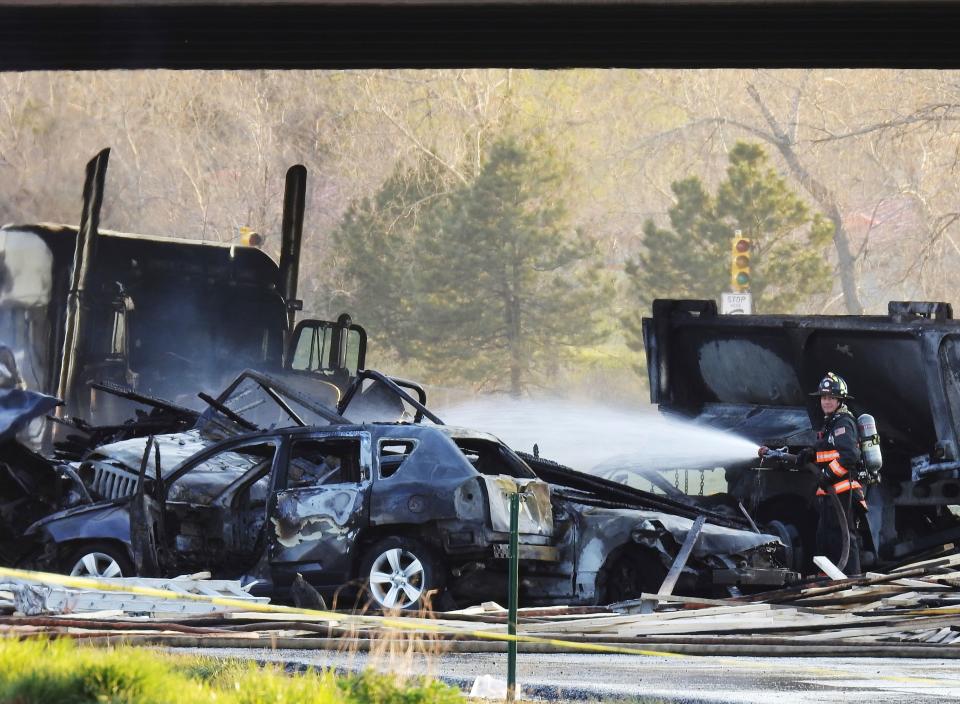 A firefighter sprays water on the wreckage in Lakewood, Colo., after a deadly collision on Interstate 70 near the Colorado Mills Parkway, April 25, 2019.