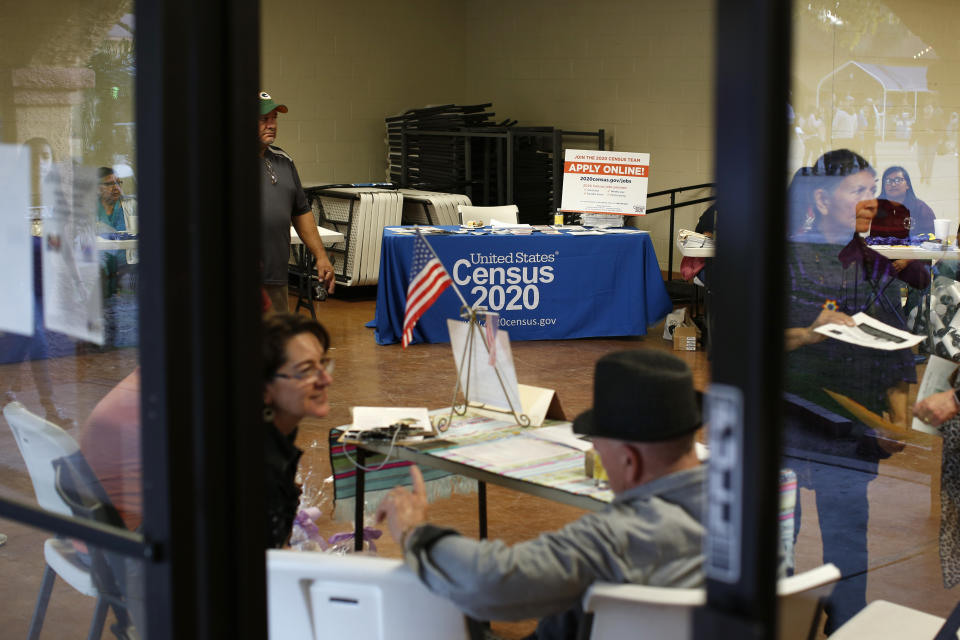 In this Feb. 8, 2020, photo, people volunteer to get people registered to vote and a booth offering employment for the upcoming 2020 census stands in the background, during the celebration of the town's 45th year since it was incorporated, in Guadalupe, Ariz. Today, nearly a third of Guadalupe's 6,500 residents say they are Native American and about 75% of all races identify as Hispanic. A third also struggle with poverty in a community where the median annual household income is around $32,000 and the average owner-occupied home is valued at less than $90,000. (AP Photo/Dario Lopez-MIlls)