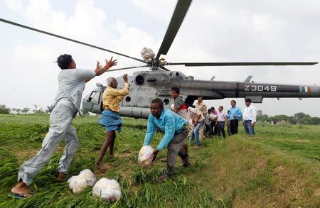 Food parcels are unloaded from an Indian Air Force helicopter to be distributed among those affected by flooding on the outskirts of Allahabad, India, August 25, 2016. REUTERS/Jitendra Prakash