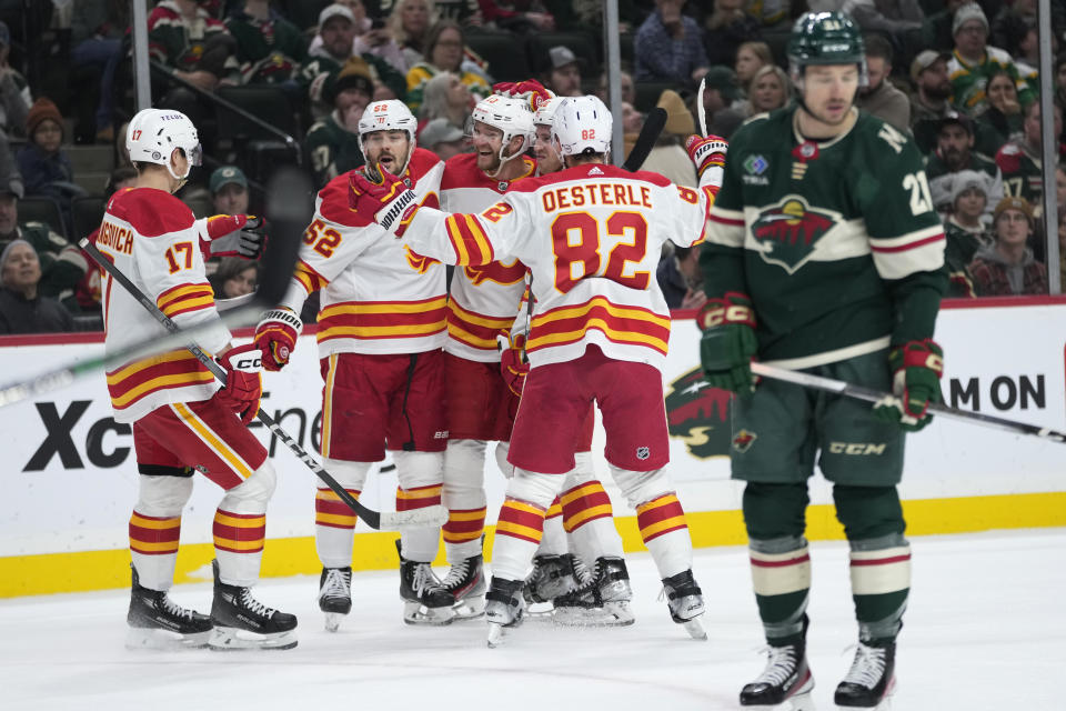 Calgary Flames center Jonathan Huberdeau, third from left, celebrates with teammates after scoring against the Minnesota Wild during the first period of an NHL hockey game Tuesday, Jan. 2, 2024, in St. Paul, Minn. (AP Photo/Abbie Parr)