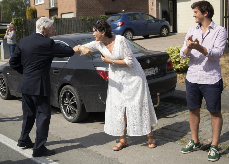 British RAF veteran George Sutherland, 98, left, elbow bumps a greeting with a bystander who came out to cheer him on during a VE Day charity walk to raise funds for Talbot House in Poperinge, Belgium, Friday, May 8, 2020. Sutherland walked from the Lijssenthoek war cemetery to Talbot house to raise money for the club which is currently closed due to coronavirus lockdown regulations. The club, founded in 1915 was a place for British soldiers to rest during both the First and Second World Wars. (AP Photo/Virginia Mayo)