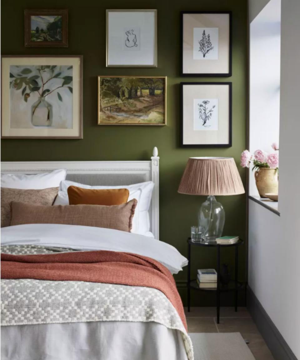 A bedroom with a dark green wall and picture gallery
