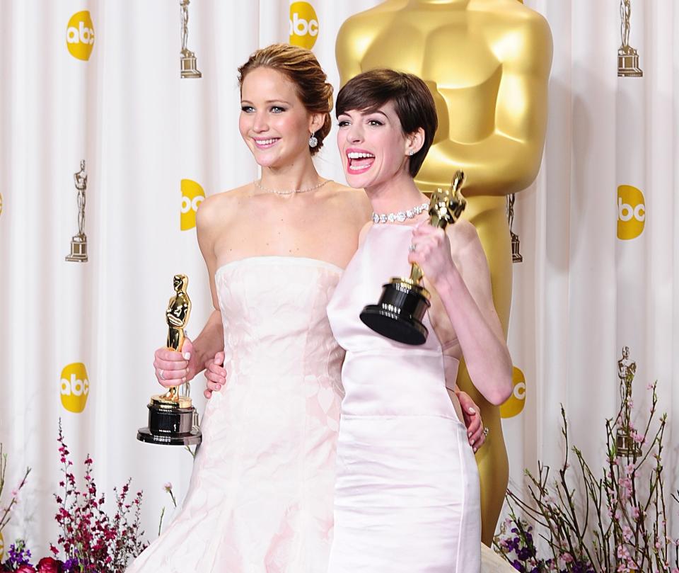 Jennifer Lawrence and Anne Hathaway posing with their Oscars