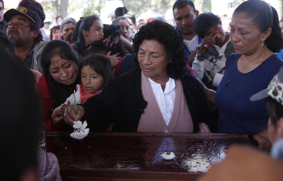 A woman sprinkles holy water, using a flower, on the coffin of a person who died when a gas pipeline exploded in the village of Tlahuelilpan, Mexico, Sunday Jan. 20, 2019. A massive fireball that engulfed locals scooping up fuel spilling from a pipeline ruptured by thieves in central Mexico killed dozens of people and badly burned dozens more on Jan. 18. (AP Photo/Claudio Cruz)