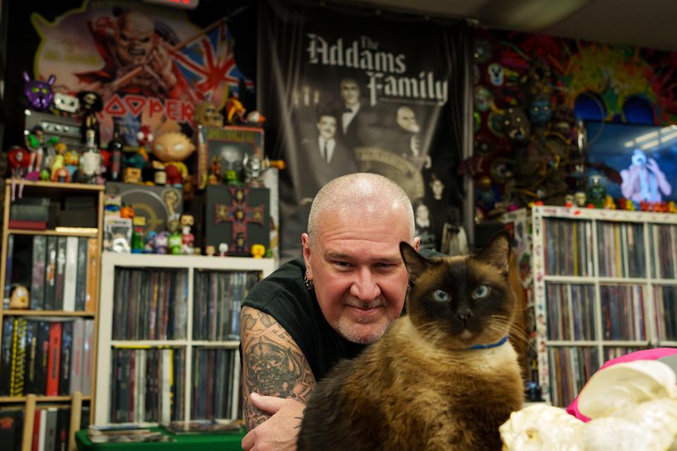 Asylum Records owner, Scott Robenalt poses for a portrait with his cat, Hopper behind the counter at Asylum Records on August 19, 2023, in Chandler, AZ.