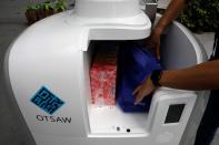 A staff member loads groceries into Carmello, an autonomous grocery delivery robot, in Singapore