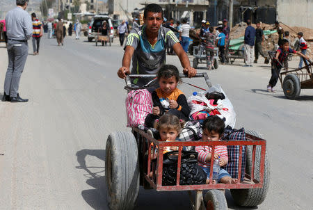 A displaced Iraqi man pushes a wheelbarrow with children as they flee after a battle between the Iraqi Counter Terrorism Service and Islamic State militants in western Mosul, Iraq, April 22, 2017. REUTERS/Muhammad Hamed